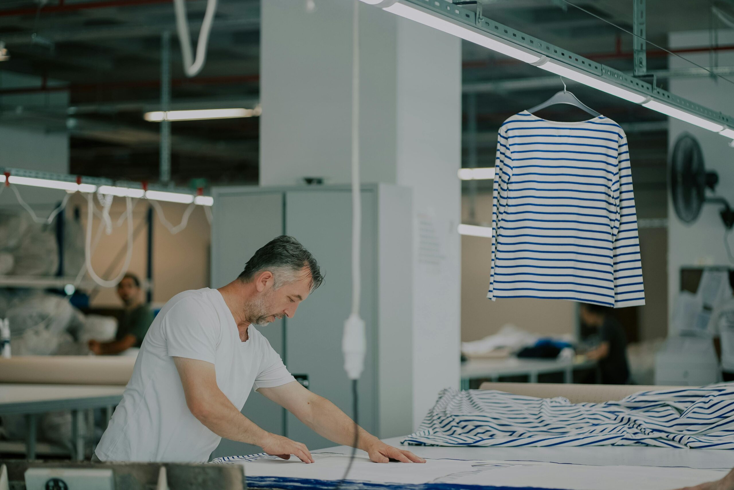Adult male in a textile workshop working with striped fabric indoors.